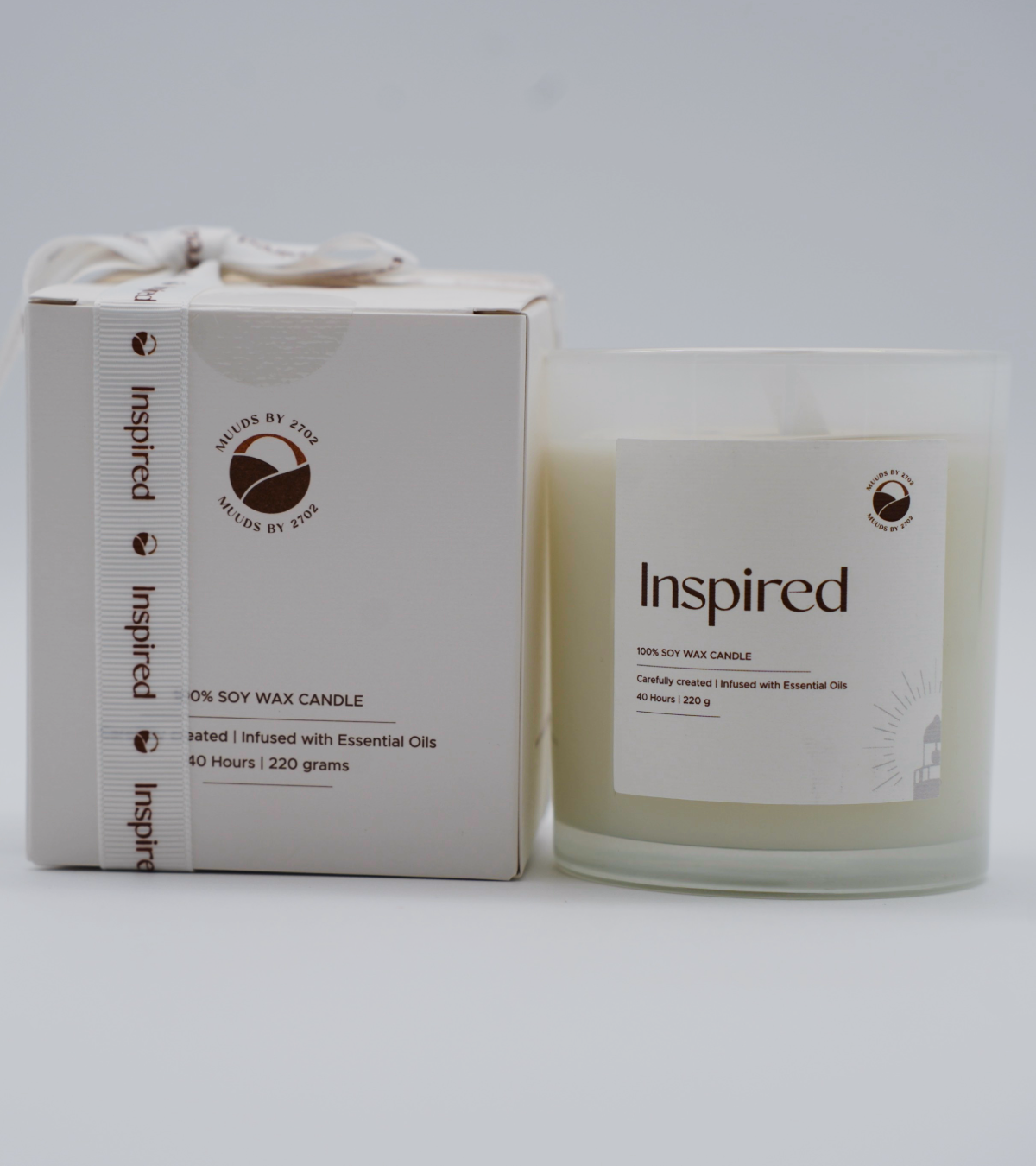 Candle with packaging labeled 'Inspired' on a white background