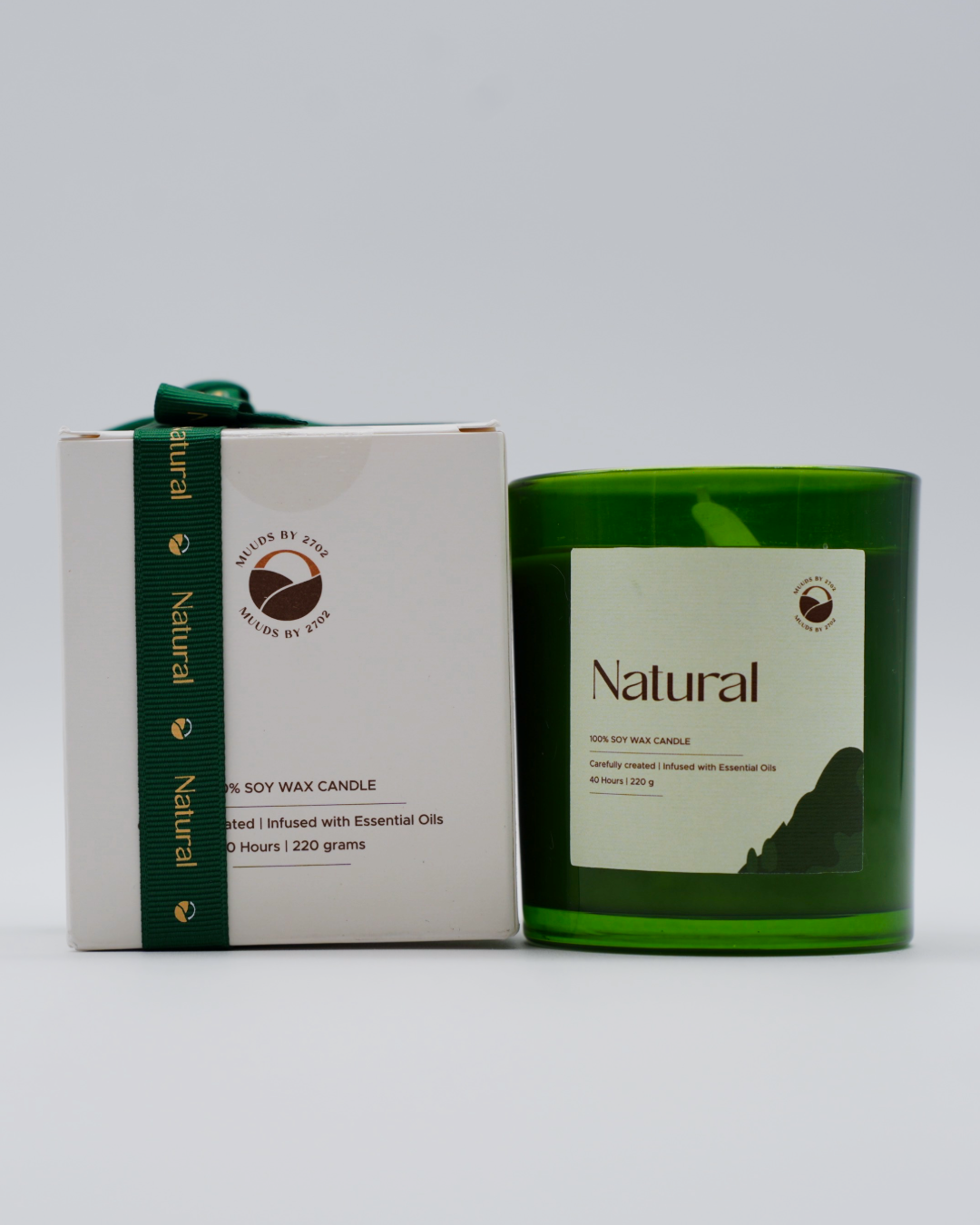 Green candle with a white label and box on a gray background